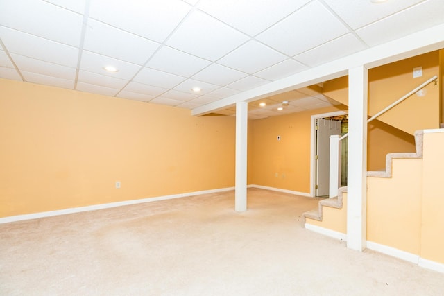 basement featuring a paneled ceiling and carpet