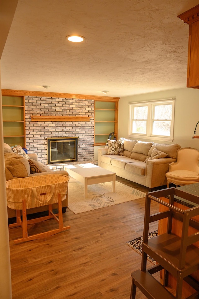 living room featuring hardwood / wood-style floors, a brick fireplace, and a textured ceiling