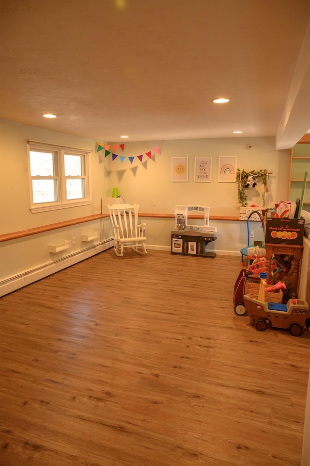 rec room with hardwood / wood-style flooring and baseboard heating