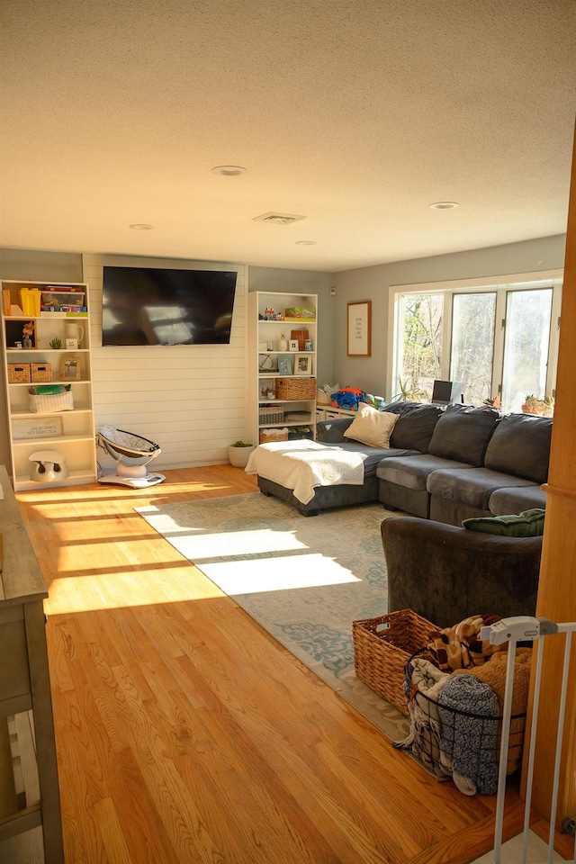 living room with hardwood / wood-style flooring, built in features, and a textured ceiling