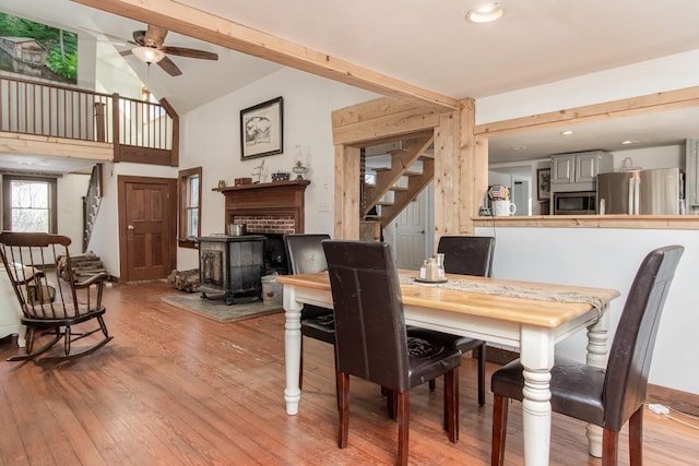 dining space featuring ceiling fan, beam ceiling, high vaulted ceiling, and light hardwood / wood-style flooring