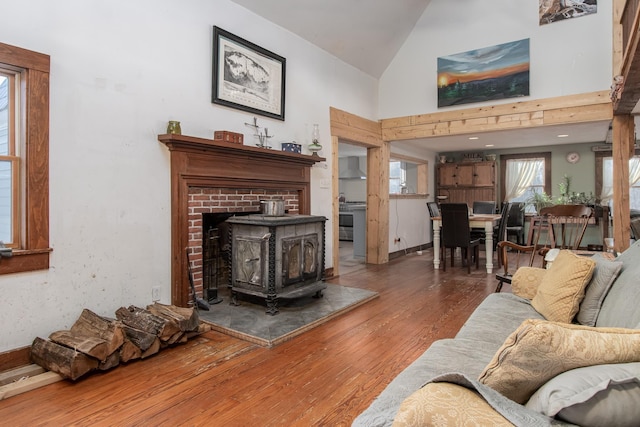 living room with a wood stove, hardwood / wood-style floors, and high vaulted ceiling