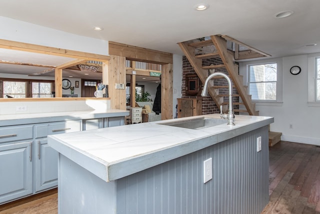 kitchen with wood-type flooring, sink, and a kitchen island with sink