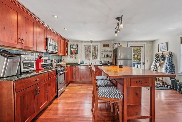 kitchen with wood counters, sink, light wood-type flooring, appliances with stainless steel finishes, and backsplash