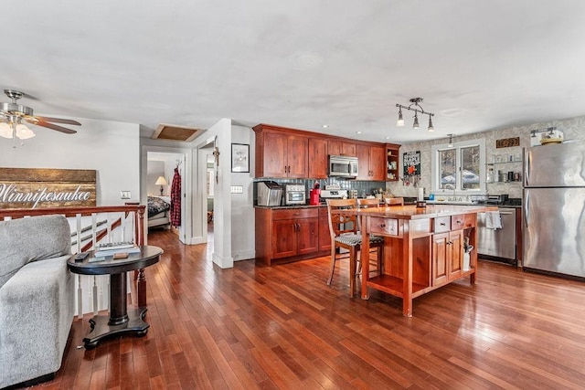 kitchen featuring a breakfast bar area, dark wood-type flooring, stainless steel appliances, a center island, and decorative backsplash