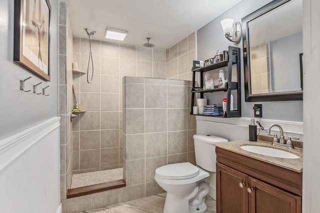 bathroom with tiled shower, vanity, and toilet