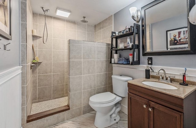 bathroom with vanity, toilet, and tiled shower