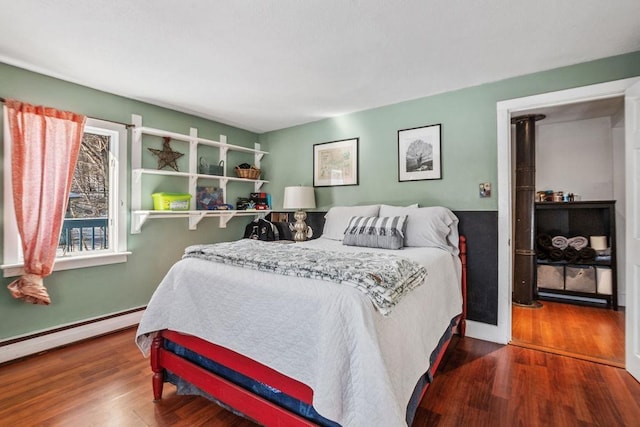 bedroom with a baseboard heating unit and dark hardwood / wood-style floors