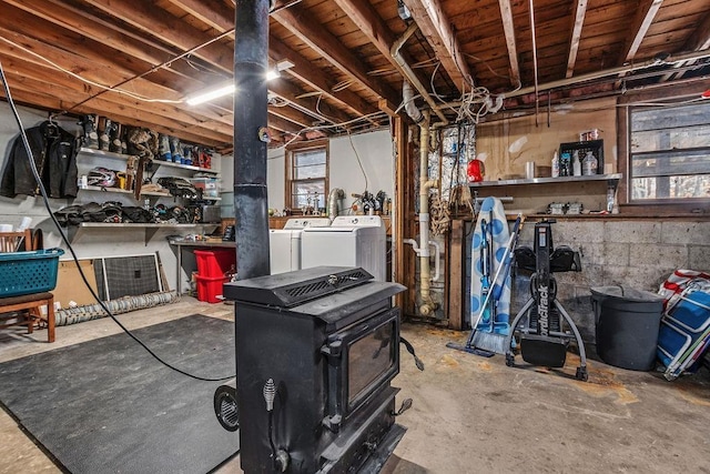 basement featuring washing machine and clothes dryer and a wood stove