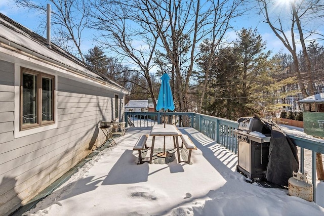 snow covered patio with area for grilling and a deck