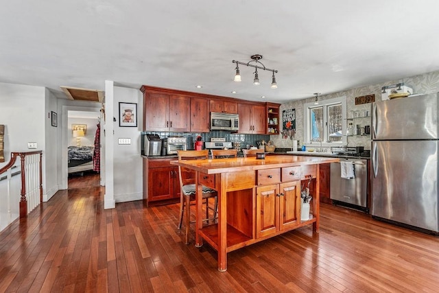 kitchen with appliances with stainless steel finishes, dark wood-type flooring, butcher block countertops, and decorative backsplash