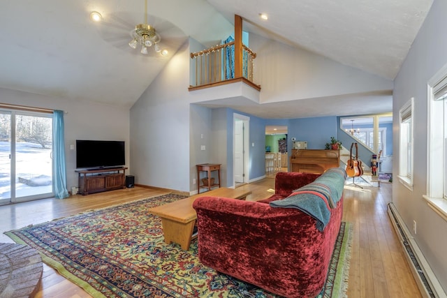 living room featuring ceiling fan, a baseboard radiator, high vaulted ceiling, and light hardwood / wood-style flooring