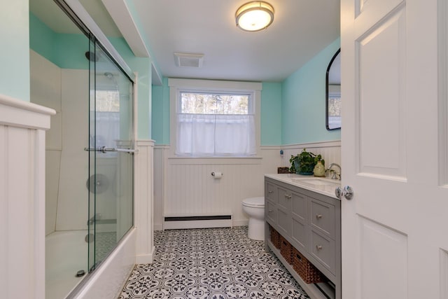 full bathroom with a baseboard radiator, tile patterned flooring, enclosed tub / shower combo, vanity, and toilet