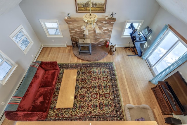 living room with a baseboard radiator, a wood stove, and hardwood / wood-style floors