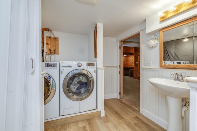 clothes washing area featuring sink, washing machine and dryer, and light wood-type flooring