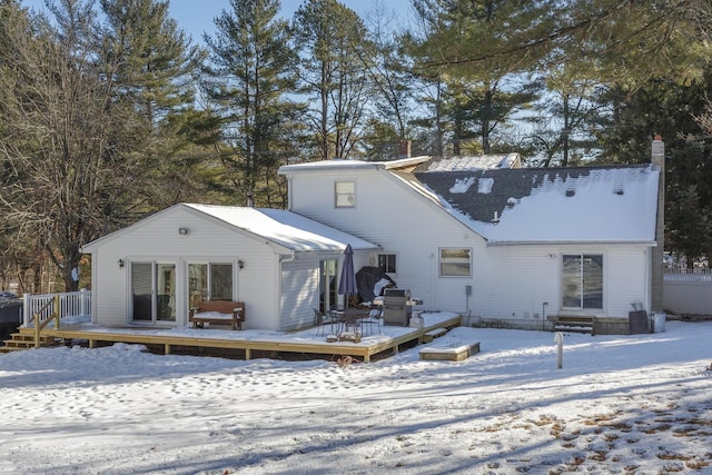 snow covered rear of property with a deck