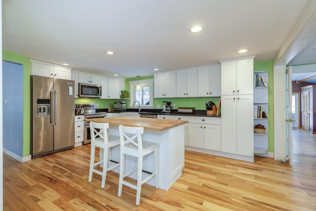 kitchen featuring white cabinetry, appliances with stainless steel finishes, a center island, and butcher block countertops