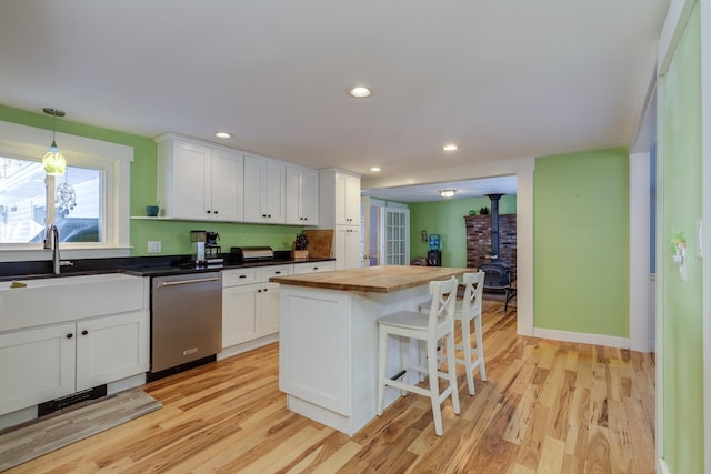 kitchen featuring white cabinetry, dishwasher, a center island, and wood counters