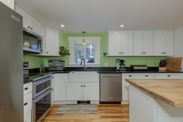 kitchen with wood counters, sink, white cabinetry, and appliances with stainless steel finishes