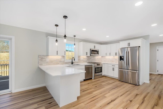 kitchen with hanging light fixtures, appliances with stainless steel finishes, sink, and white cabinets