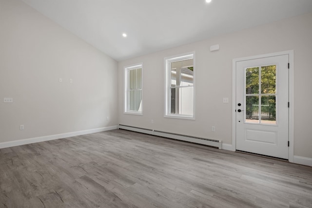 empty room with lofted ceiling, a baseboard heating unit, and light wood-type flooring