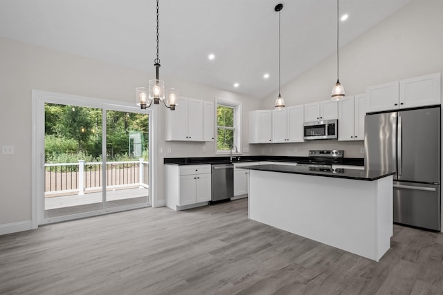 kitchen featuring sink, light hardwood / wood-style flooring, appliances with stainless steel finishes, hanging light fixtures, and white cabinets