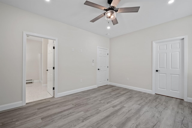 empty room featuring baseboard heating, ceiling fan, and light hardwood / wood-style flooring