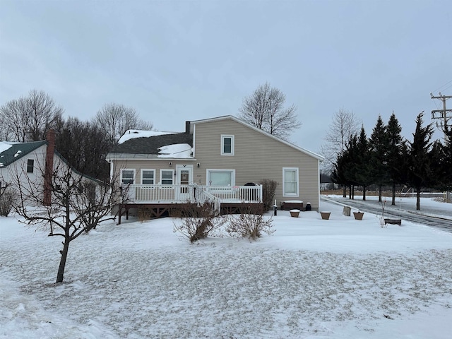 snow covered house featuring a wooden deck