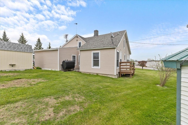 rear view of property featuring a wooden deck, a yard, and a storage unit