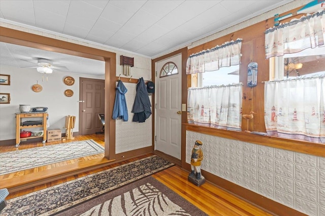 foyer entrance with crown molding, wood-type flooring, and ceiling fan