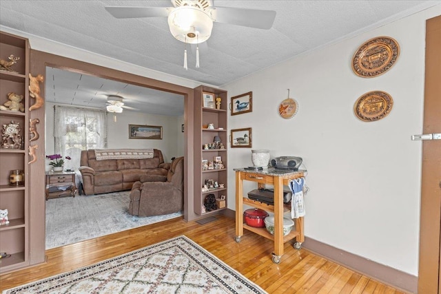 living room with crown molding, a textured ceiling, wood-type flooring, and ceiling fan