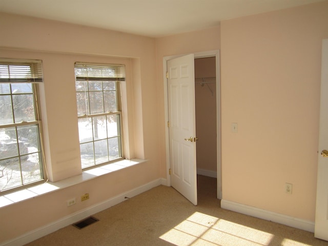 unfurnished bedroom featuring multiple windows, light colored carpet, and a closet