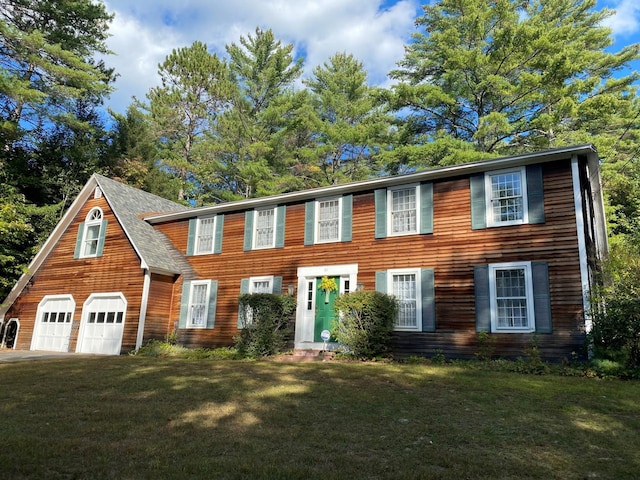 colonial inspired home featuring a garage and a front lawn