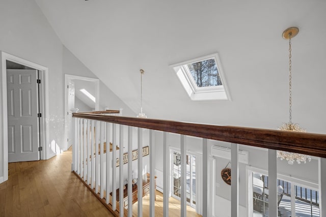 hallway with lofted ceiling with skylight, a chandelier, and hardwood / wood-style floors