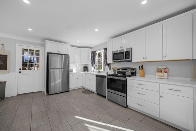 kitchen featuring ornamental molding, appliances with stainless steel finishes, sink, and white cabinets