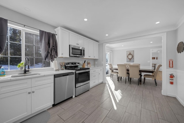 kitchen with light stone counters, sink, white cabinets, and appliances with stainless steel finishes