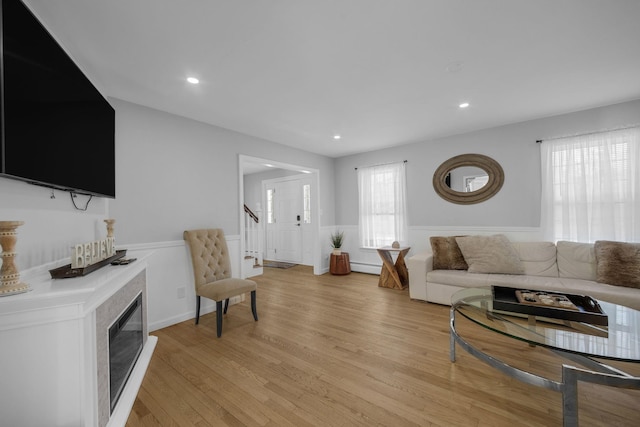 living room featuring a baseboard heating unit, a wealth of natural light, and light wood-type flooring