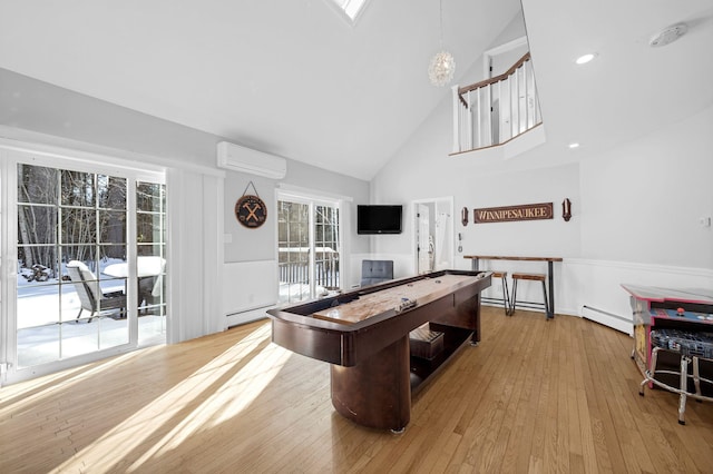 recreation room featuring a wall mounted air conditioner, light wood-type flooring, high vaulted ceiling, and a baseboard heating unit