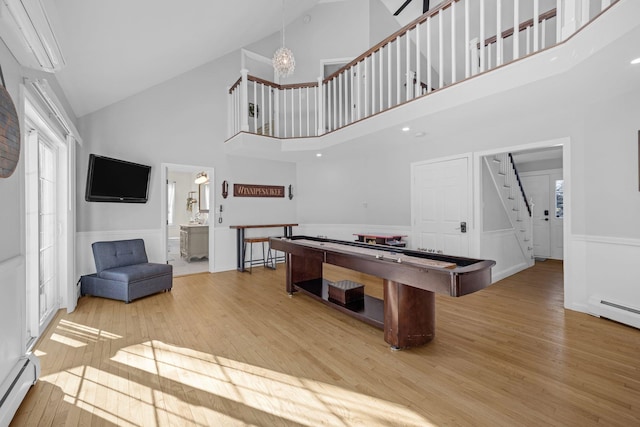 game room featuring a baseboard radiator, high vaulted ceiling, and light hardwood / wood-style floors