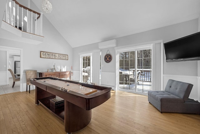 rec room featuring hardwood / wood-style flooring, a wall mounted air conditioner, high vaulted ceiling, and a baseboard heating unit