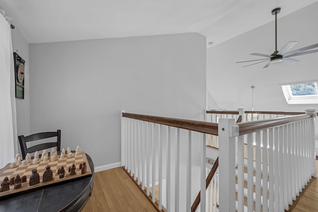 interior space with ceiling fan, vaulted ceiling with skylight, and hardwood / wood-style floors