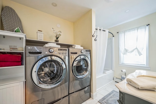 clothes washing area with separate washer and dryer, light tile patterned floors, and baseboard heating