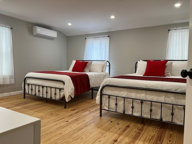 bedroom featuring a wall unit AC and light hardwood / wood-style floors