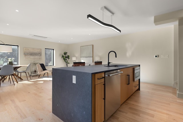 kitchen featuring sink, light hardwood / wood-style flooring, dishwasher, an island with sink, and wall oven