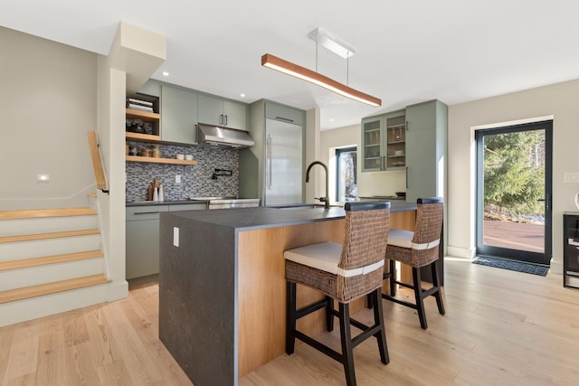 kitchen featuring light hardwood / wood-style flooring, a center island with sink, tasteful backsplash, and a kitchen bar