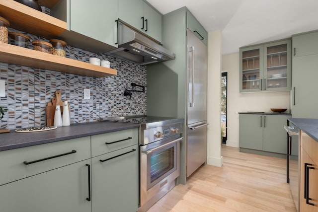 kitchen with green cabinets, exhaust hood, and appliances with stainless steel finishes