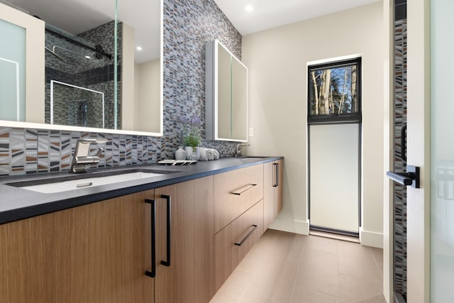 bathroom with vanity, a tile shower, tile patterned floors, and decorative backsplash