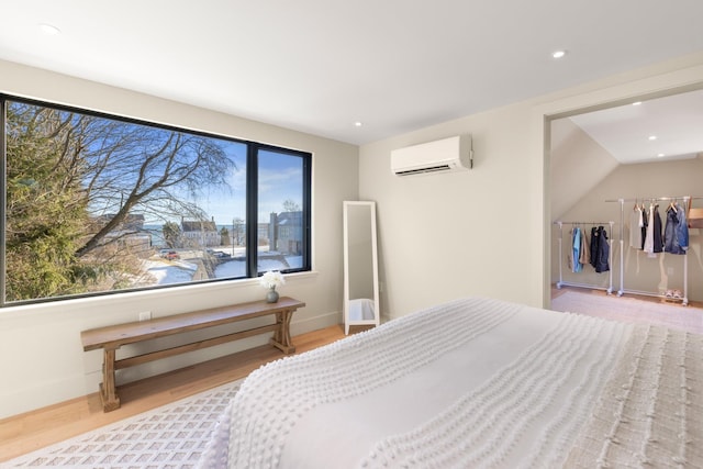 bedroom with a wall mounted air conditioner, light hardwood / wood-style flooring, and a water view