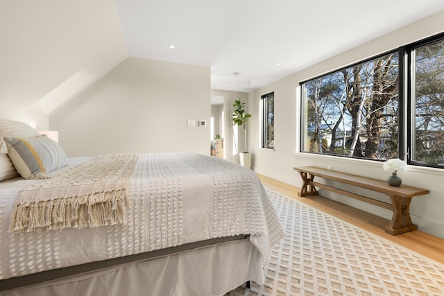 bedroom featuring vaulted ceiling, light hardwood / wood-style floors, and multiple windows