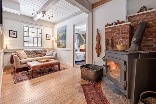 living area featuring wood ceiling, beam ceiling, light hardwood / wood-style flooring, and a wood stove